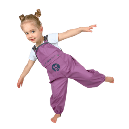 Child wearing waterproof kids overalls jumping and playing, flexible grubberalls designed for outdoor play